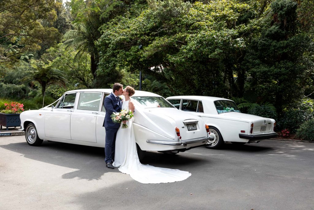 bride and groom by wedding cars