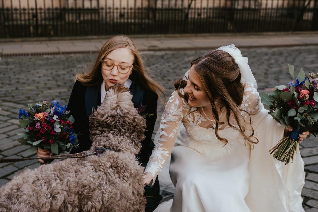 two brides in dress and suit with dog