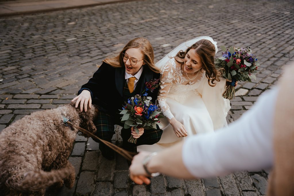 two brides in dress and suit with dog