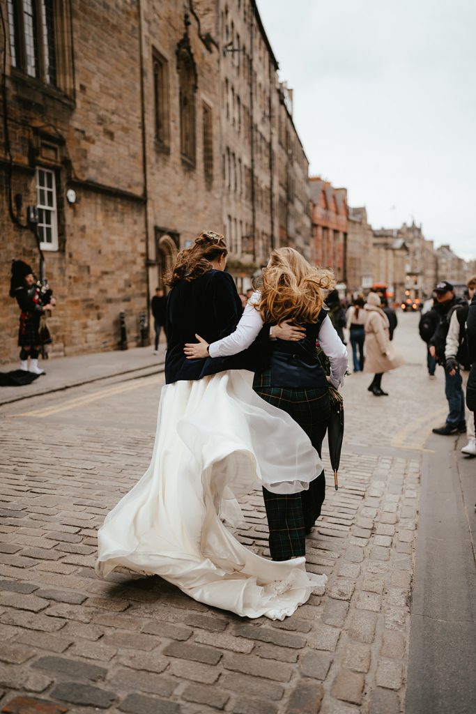 two brides in dress and suit walking in the wind