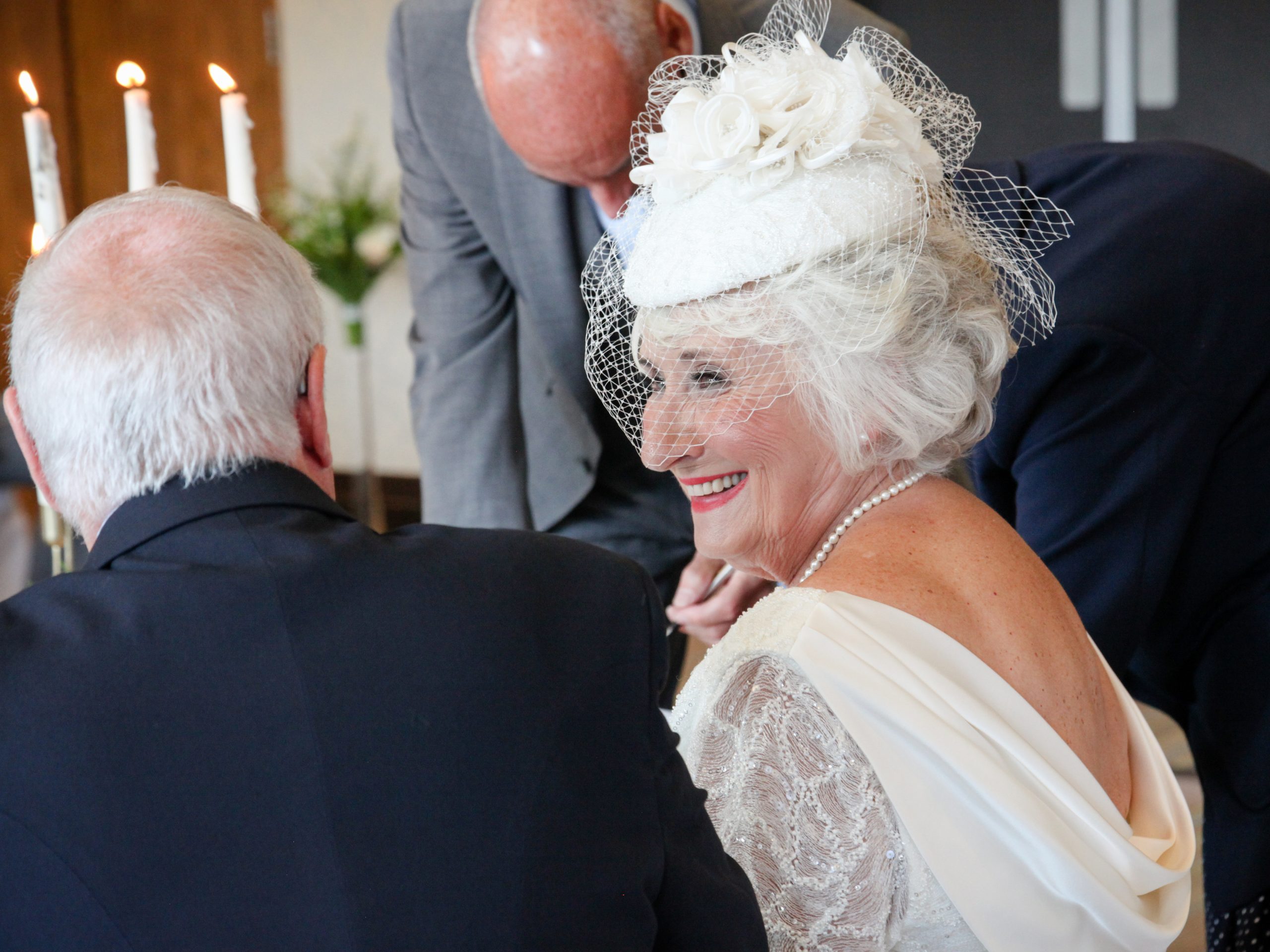 mature bride in cowl neck ress with pillar box hat