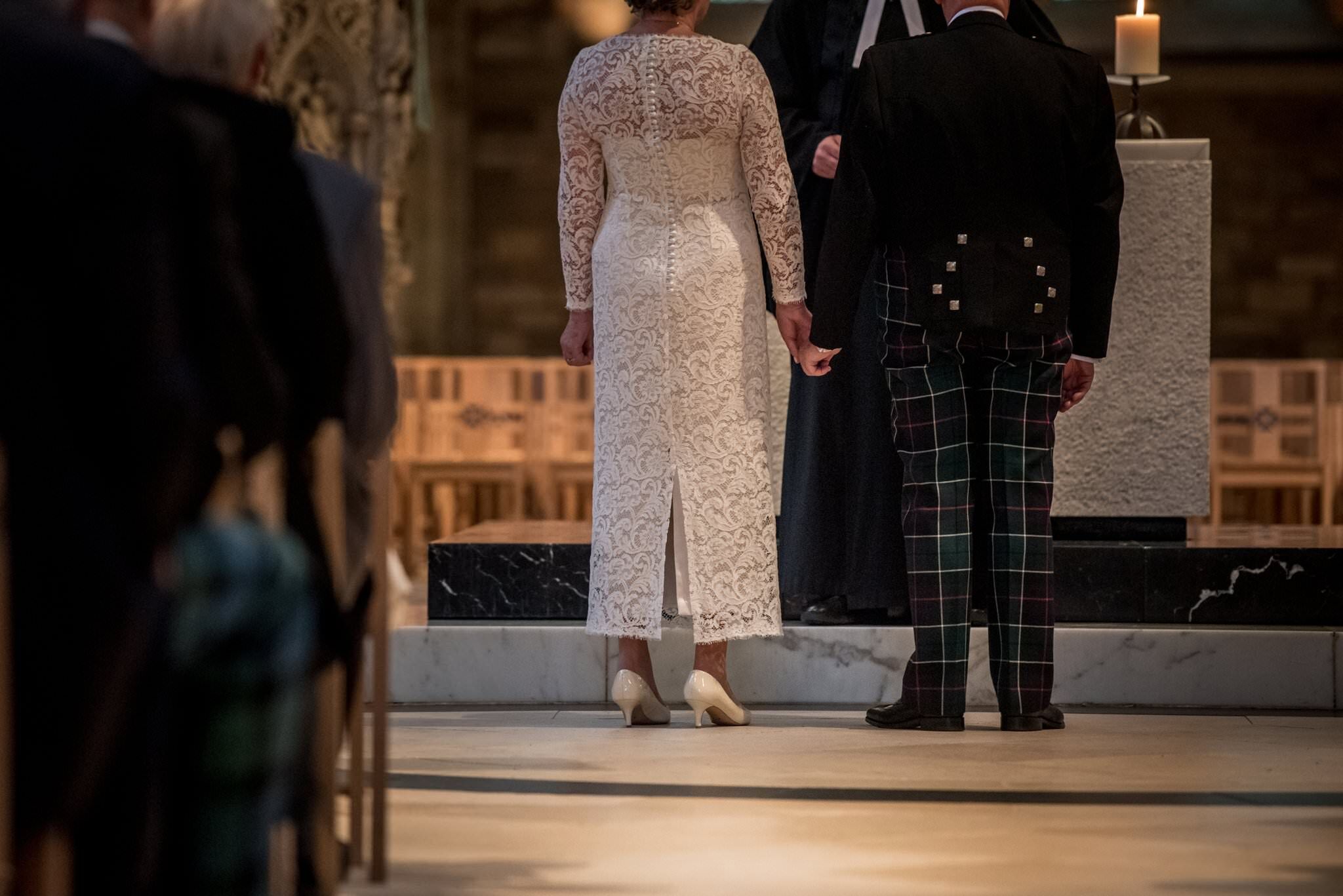 Back view of mature bride in lace wedding dress with silk button and loop detail